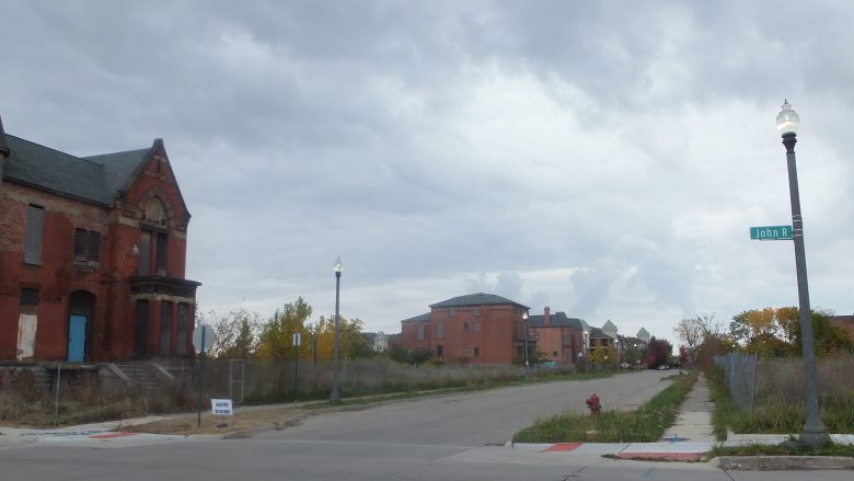 Das Bild zeigt einen Straßenzug im Vorort von Detroit, der vom Zerfall geprägt ist, mit Häusern , die verrotten, die Straßen sind menschenleer. 