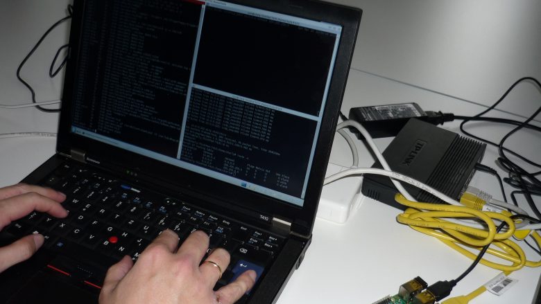 Das Bild zeigt einen Hacker an seinem Rechner mit Quellcode.