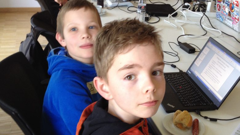 Das Foto zeigt zwei Jungs, die beim Hackday vor dem Rechner sitzen und hacken. 